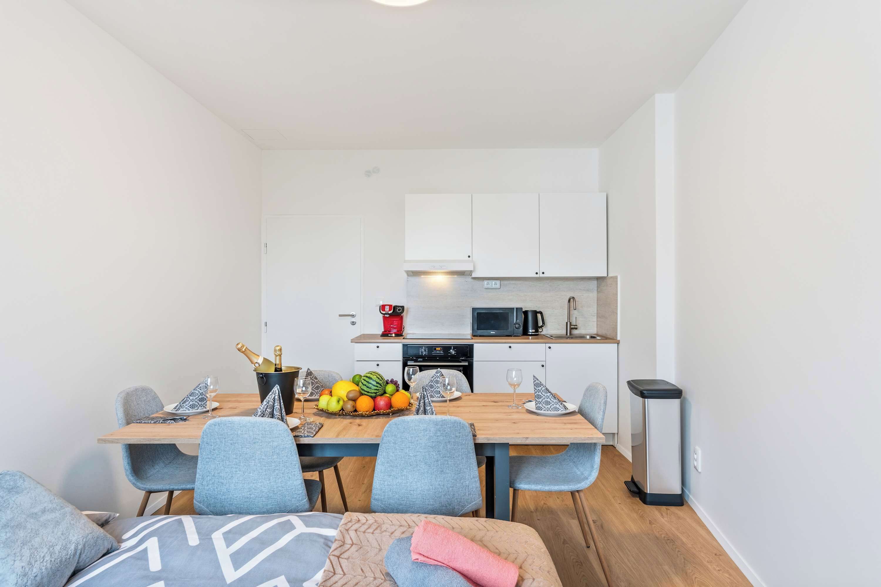 A compact kitchen with white cabinets, a microwave, and a coffee machine.