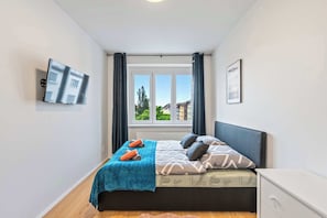 Une chambre à coucher avec un lit, une fenêtre, une télévision et une petite table de chevet.