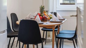 A dining area with a round table, black chairs, a fruit bowl, and a hanging light fixture. - Historic Prague Residence Apartworld (Praha)