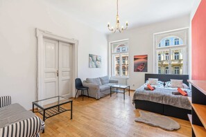 Ein Zimmer mit einem Bett, einem Schlafsofa, einem Sessel, einem Glastisch und einem Teppich.
