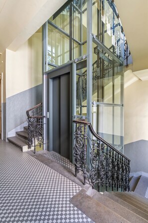 Eine Treppe mit aufwendiger Metallgeländerung und einem Schachbrettmuster auf dem Boden.