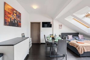 Een moderne slaapkamer met een dakraam, een zithoek met een tafel en stoelen, en een schilderij aan de muur.