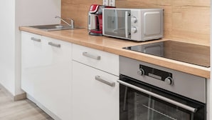 A modern kitchen with white cabinets, a wooden countertop, a built-in oven, a microwave, and a coffee maker. - Prague Serenity Suite Apartworld (Praha)