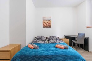 Ein Schlafzimmer mit einem Bett, zwei Nachttischen, einem Schreibtisch und einem Stuhl.