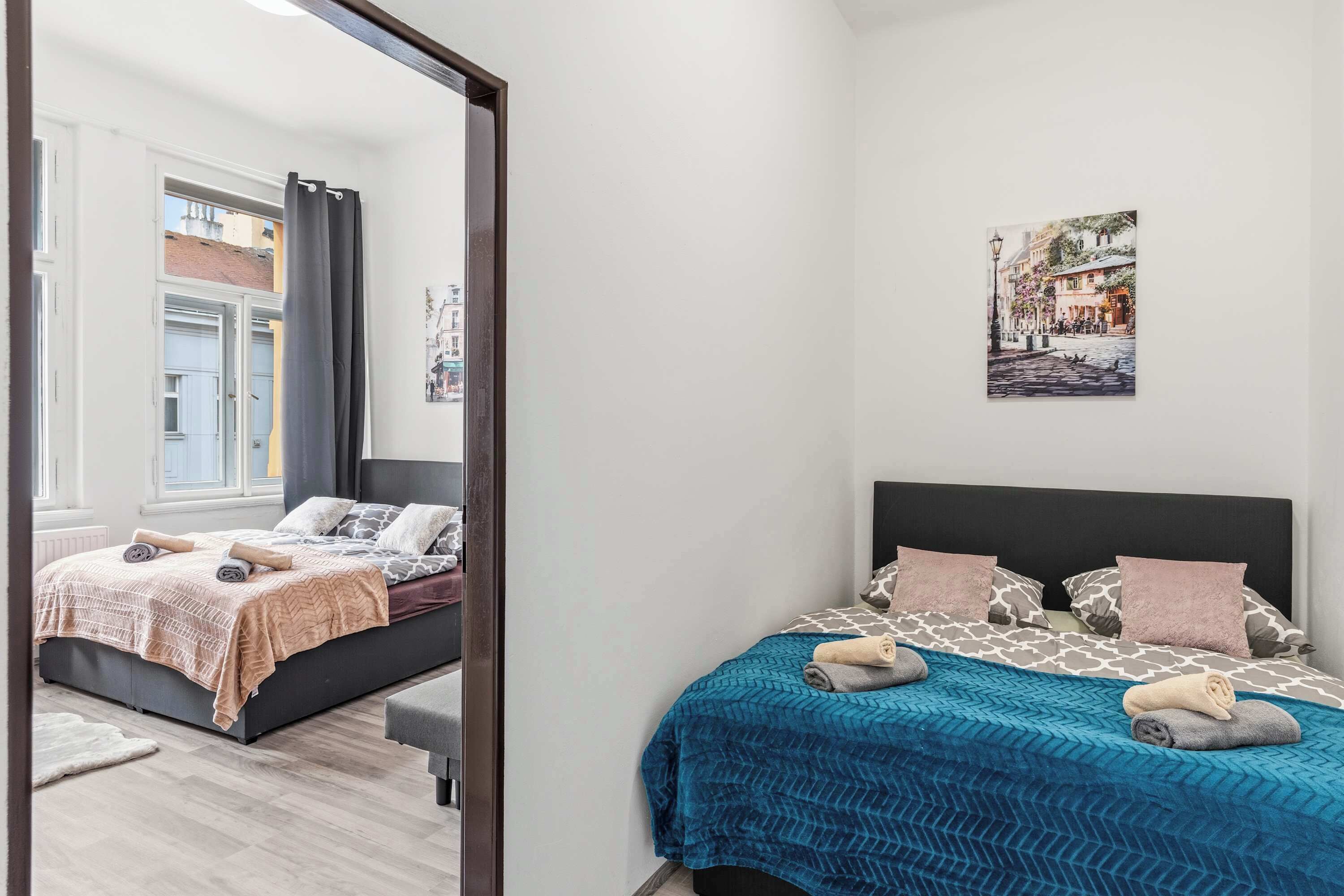 Un dormitorio con cama, espejo, un cuadro y vista a la calle.