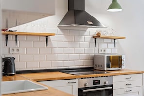 A kitchen with white subway tiles, a microwave, a toaster, a kettle, and a wooden countertop. - City Comfort Terrace Prague (Praha)