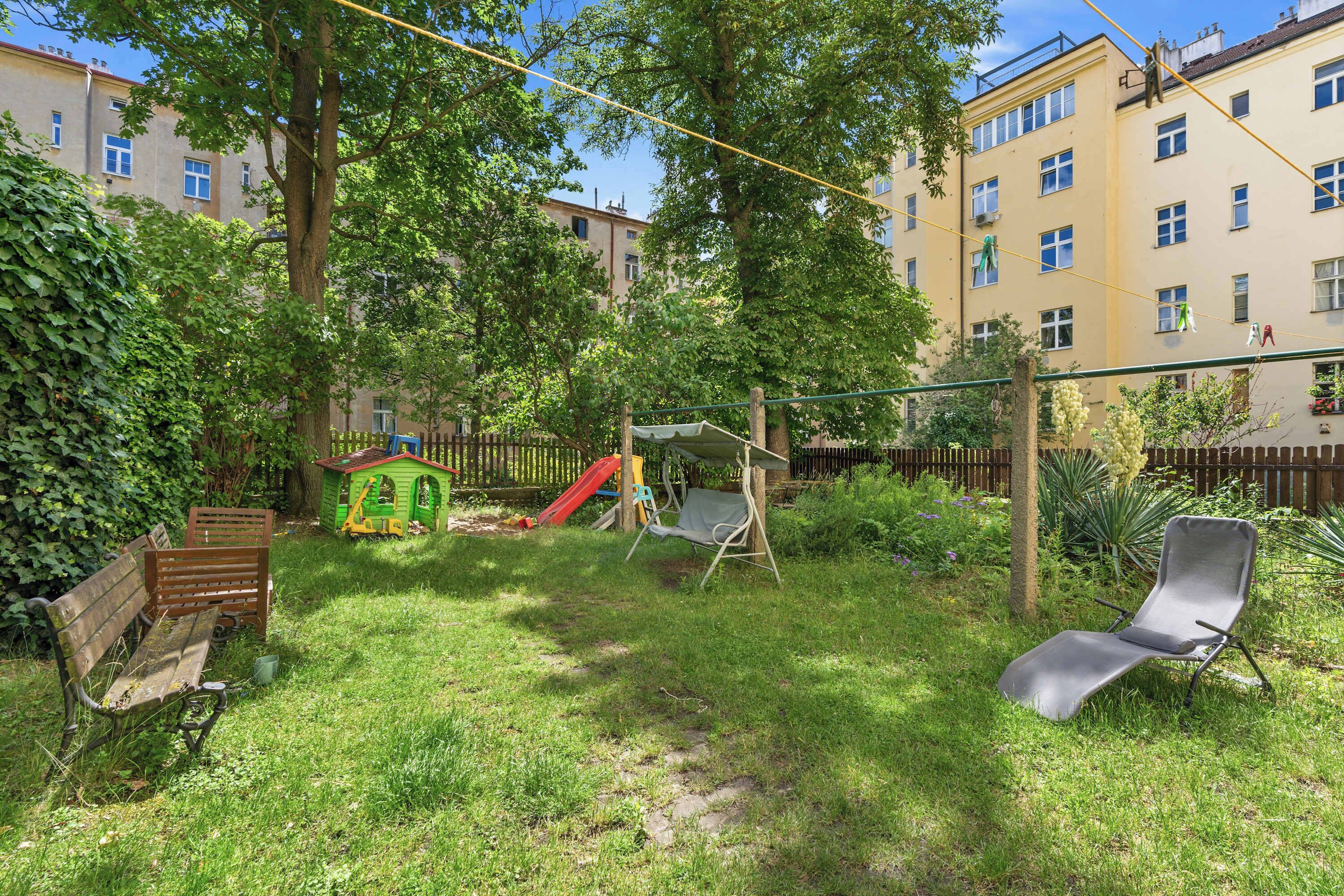 Ein Garten mit Schaukel, Rutsche, Bank und Liegestuhl.