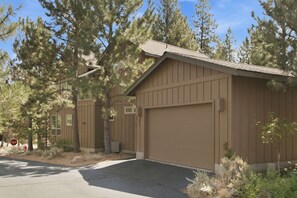 A two-story building with a garage, surrounded by trees. - River Wild at Mt Bachelor Village - Hot Tub + Pool (Bend)