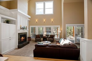 A living room with a fireplace, seating area, and large windows. - River Wild at Mt Bachelor Village - Hot Tub + Pool (Bend)
