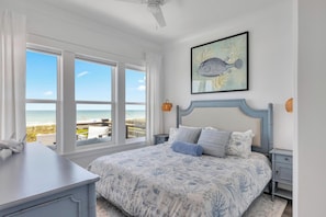 Ein Schlafzimmer mit einem Bett, einem Schreibtisch und Blick auf den Strand.