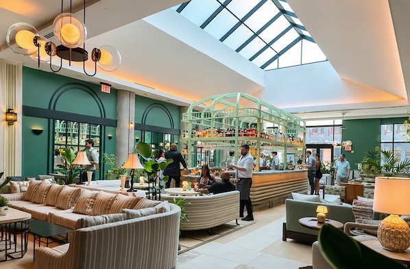Eine Hotelhalle mit Barbereich, Sitzgelegenheiten und einem Oberlicht.