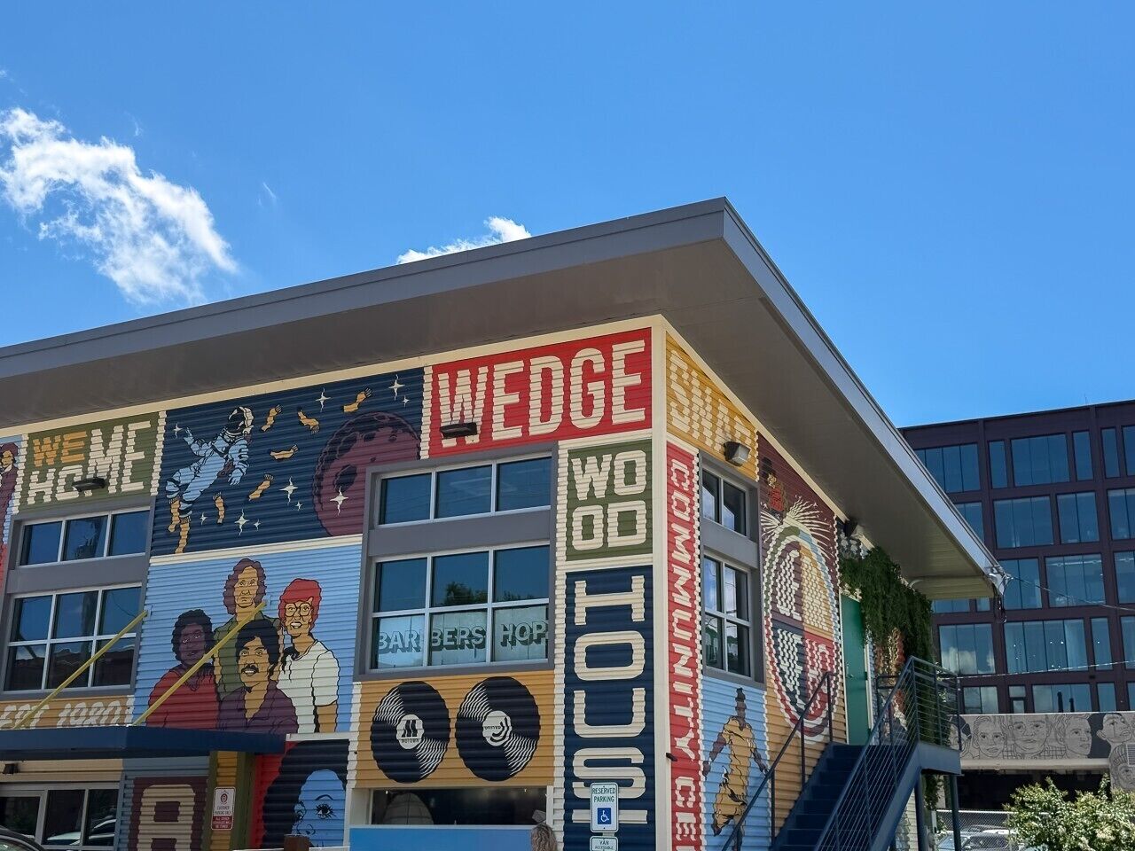 A building with a colorful mural, a large sign reading 'WEDGE WOOD HOUSE,' and a bar named 'BAR BERS HOP' on the ground floor.