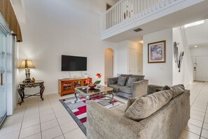 Ein Wohnzimmer mit einer Couch, einem Couchtisch, einem Fernseher und einer Treppe.