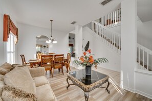 Ein geräumiges Wohnzimmer mit Sofa, Esstisch, Stühlen und einer Treppe.