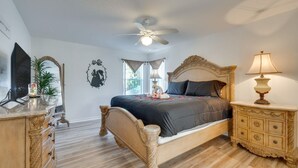 Una camera da letto con un letto, una ventola a soffitto, una lampada da comodino, un comò e uno specchio.