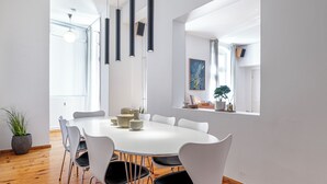 Zona pranzo moderna con tavolo rotondo, sedie bianche, lampade a sospensione e pavimento in legno.