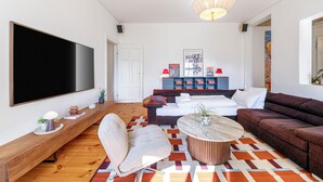 Un soggiorno moderno con un'ampia televisione a schermo piatto, un divano, un tavolino da caffè e un tappeto decorato.