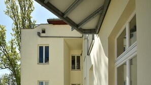 Un balcone con tavolo e sedie, una pianta in vaso e vista su un edificio con finestre.
