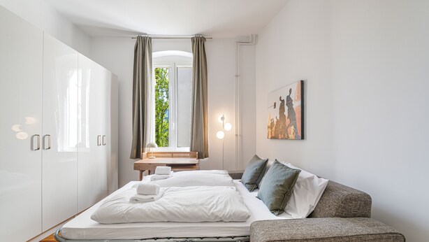 Una camera da letto con un letto, un divano, un armadio, una scrivania e una finestra con tende.