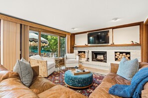 Una sala moderna con chimenea, sofá de cuero y televisor montado en la pared.