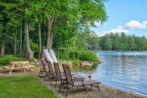 Un cadre idyllique au bord du lac, avec des tables de pique-nique, des chaises longues et un canard qui nage dans l’eau.