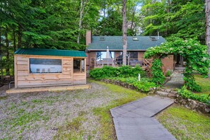 Une cabane dotée d’un toit végétalisé, d’une terrasse en bois et d’un chemin de pierre menant à l’entrée.