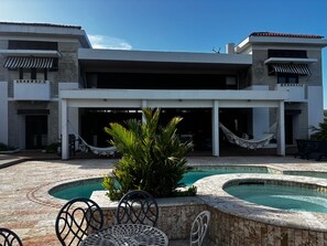 A modern hotel with a pool area, outdoor seating, and a covered patio.