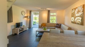 A modern living room with a sofa, a coffee table, a TV, and a dining table.