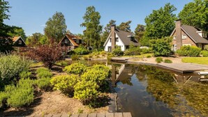 A tranquil riverside setting with traditional houses, a wooden dock, and lush greenery.