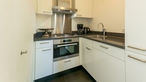 A modern kitchen with white cabinets, stainless steel appliances, and a black countertop.