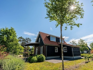 A two-story house with a sloped roof, a visible garage, and a well-maintained lawn. - Holiday Home in Lochem With Terrace (Lochem)