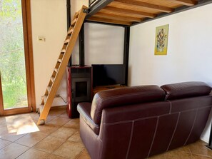 A living room with a sofa, a TV, a fireplace, and a wooden staircase.