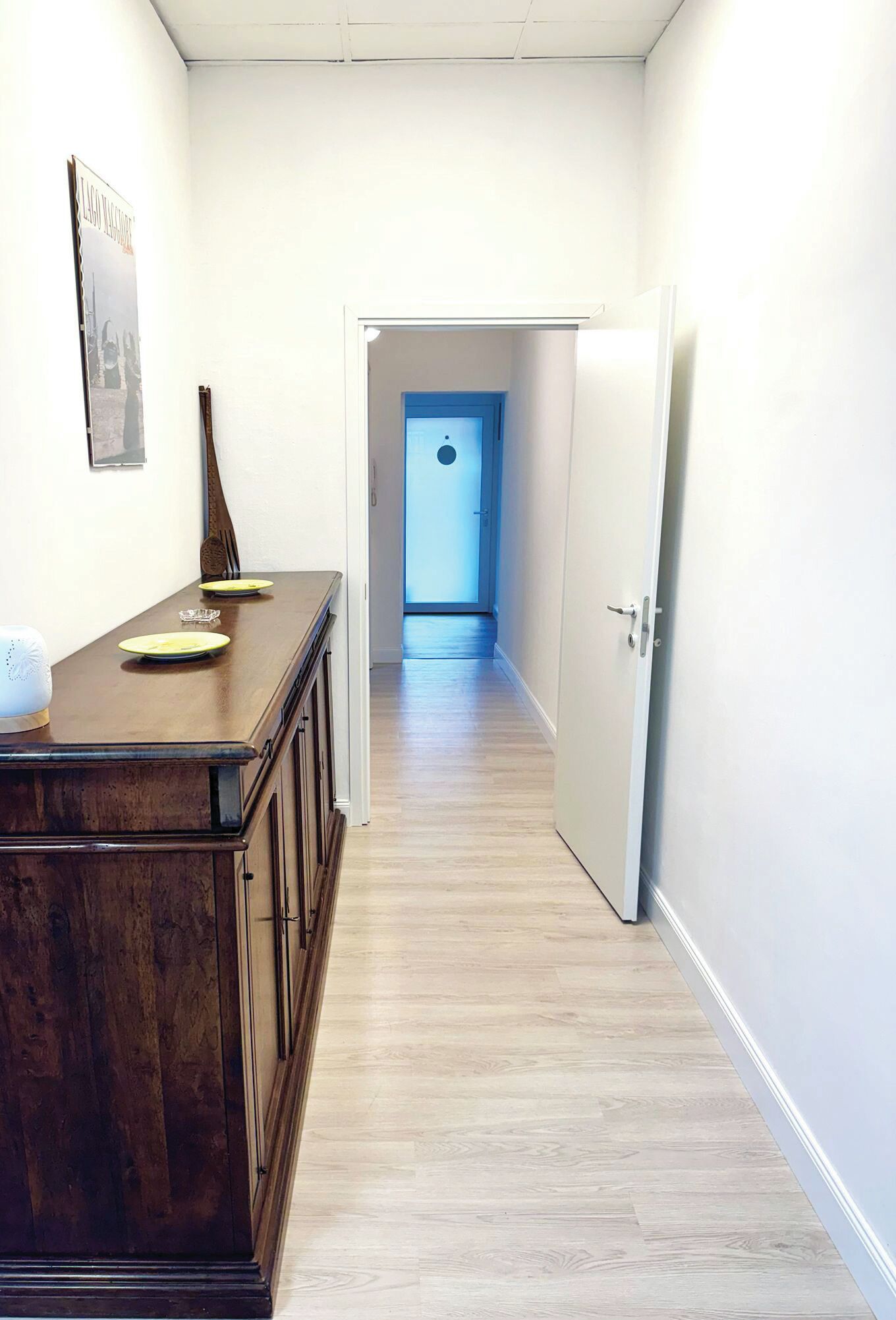Un pasillo con una mesa de madera para comer, una puerta y un cartel en la pared.