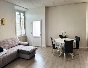 A room with a sectional sofa, a dining table with chairs, a door, and a window with curtains. - 300 m from the lake: an entire house with a private parking space and terrace (Verbania)