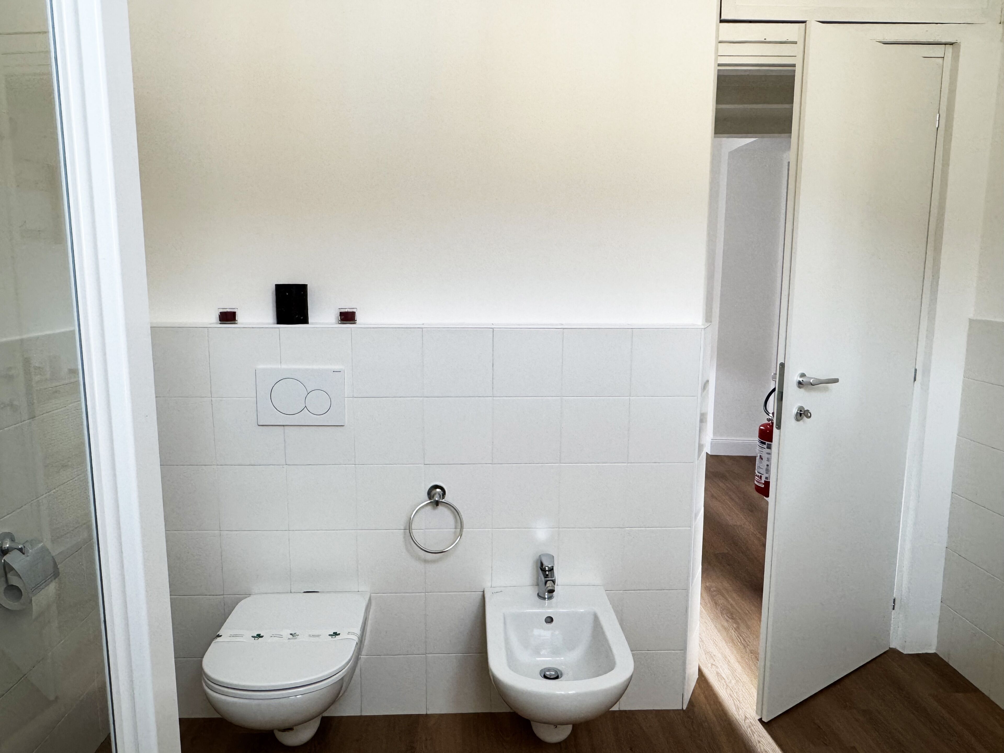 Un baño con inodoro, bidé y toallero.