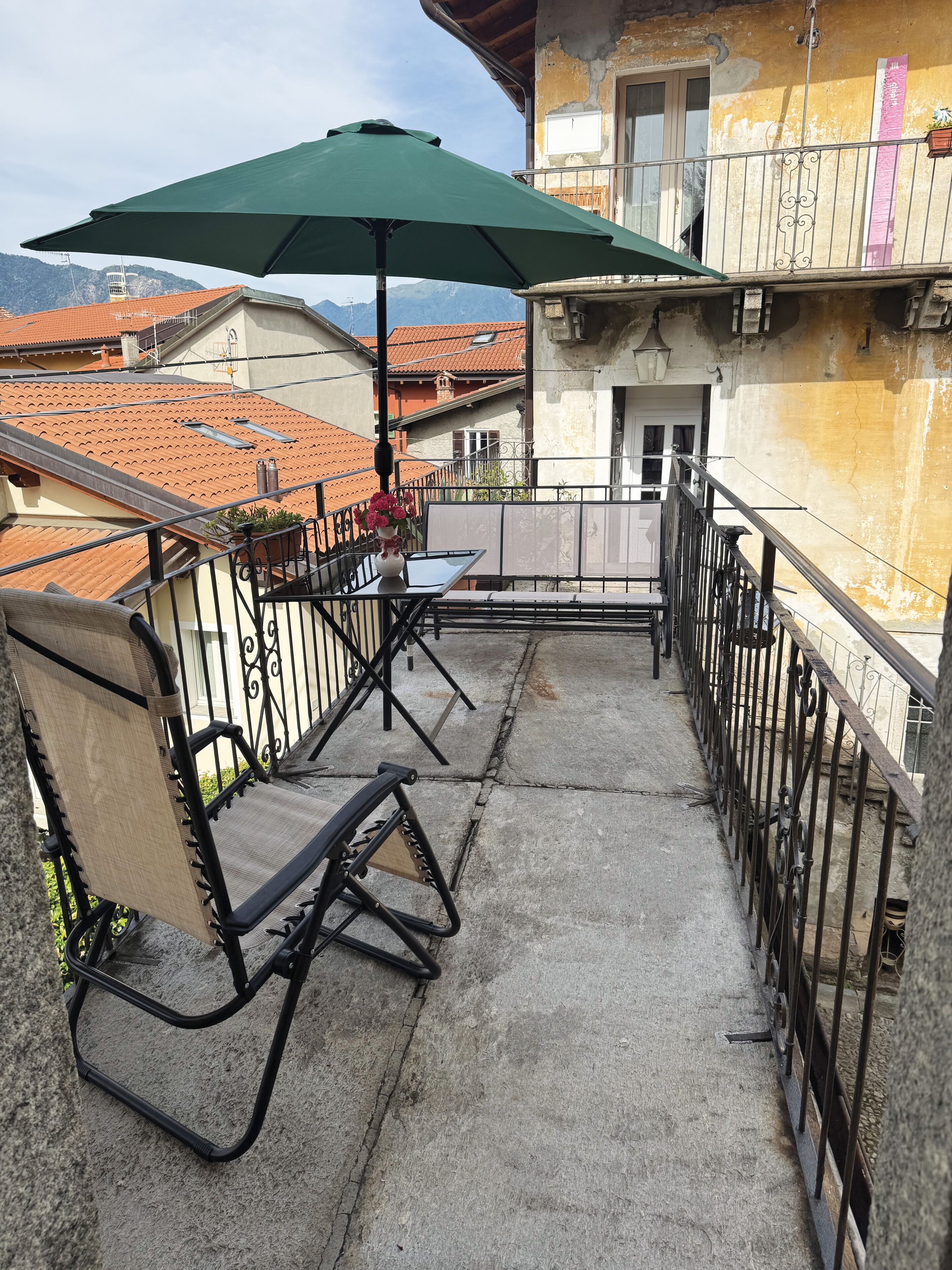 Un balcon avec une chaise, une table et un parasol.