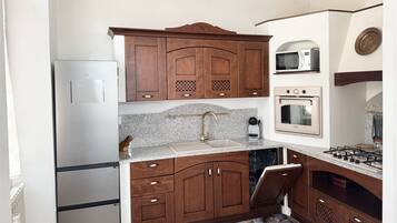 Una cocina con armarios de madera, un refrigerador de acero inoxidable, un microondas, un horno y una estufa a gas.