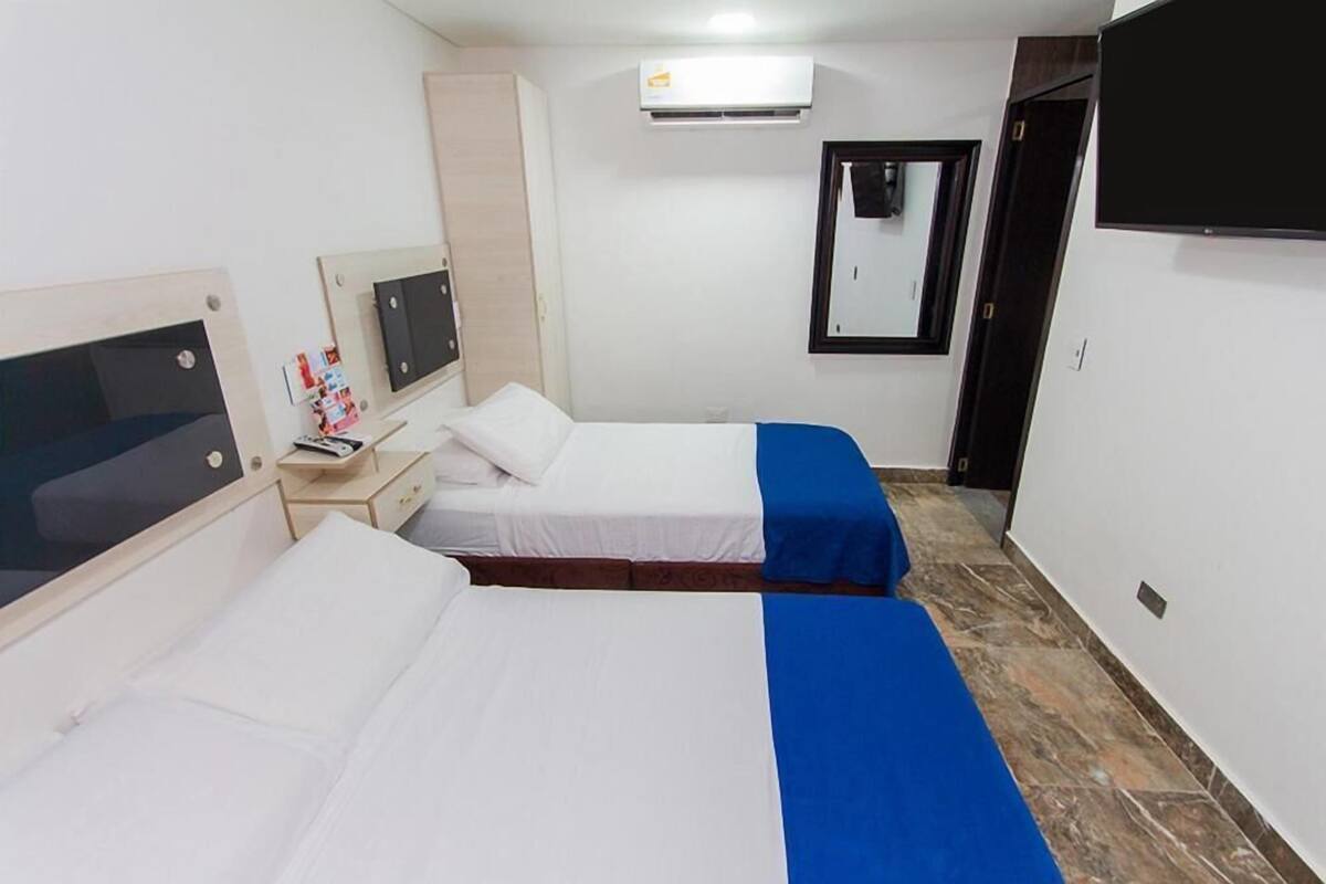Ein Hotelzimmer mit zwei Betten, einem Fernseher, einem Kleiderschrank und einer Klimaanlage.