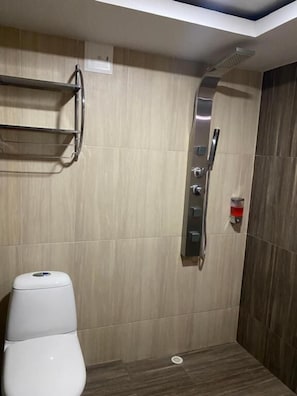 Un baño con inodoro, ducha y estante.