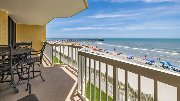 A balcony with a view of the beach, a pier, and a clear sky. - Stay @ Ocean Potion - Oceanfront - Pools - Walkable to Center Street (Folly Beach)