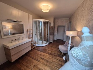 A modern bathroom with a vanity, shower, and a bed with a white headboard. - La Bâtisse de Bromont (Bromont-Lamothe)