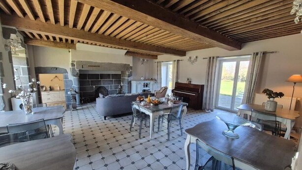 A spacious kitchen with a stone fireplace, a dining area with a table and chairs, and a view of the outdoors through large windows.