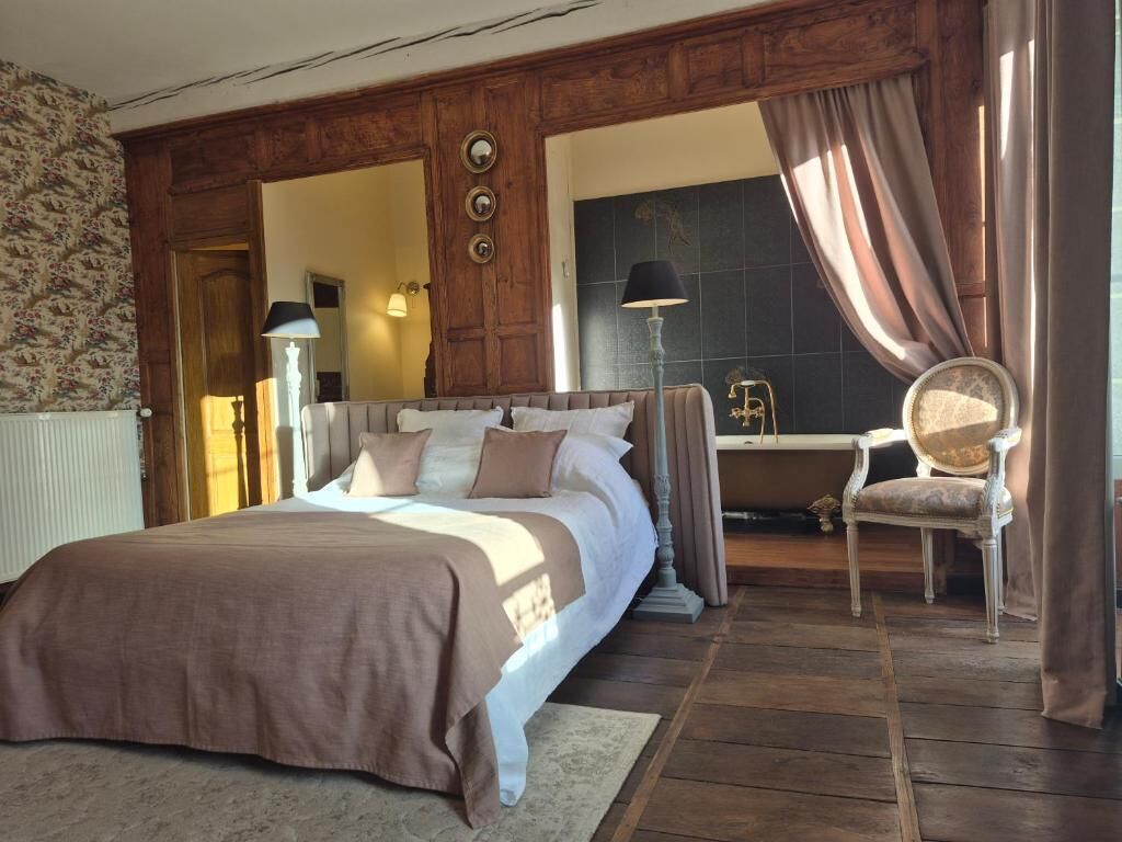 Ein Schlafzimmer mit einem großen Bett, einem Sessel und einem Schreibtisch.