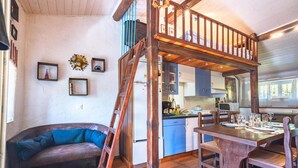 Ein rustikales Blockhaus mit Schlafzimmer im Zwischengeschoss, Essbereich und Küche.