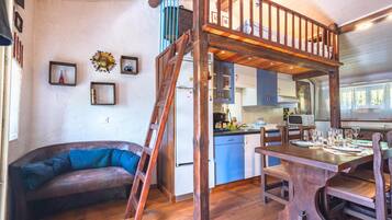 Ein rustikales Blockhaus mit Schlafzimmer im Zwischengeschoss, Essbereich und Küche.