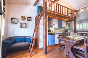Ein rustikales Blockhaus mit Schlafzimmer im Zwischengeschoss, Essbereich und Küche.