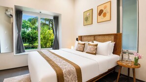 Ein Schlafzimmer mit einem großen Bett, einem Nachttisch mit Gläsern und einer Vase sowie einem Fenster mit Vorhängen.