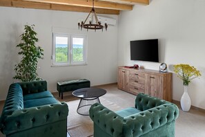 A living room with a large window, a flat-screen TV, a wooden cabinet, and green upholstered furniture. - New! Villa Ellamar, Idyllic 3-bedrooms villa in Makarska hinterland (Ivanbegovina)