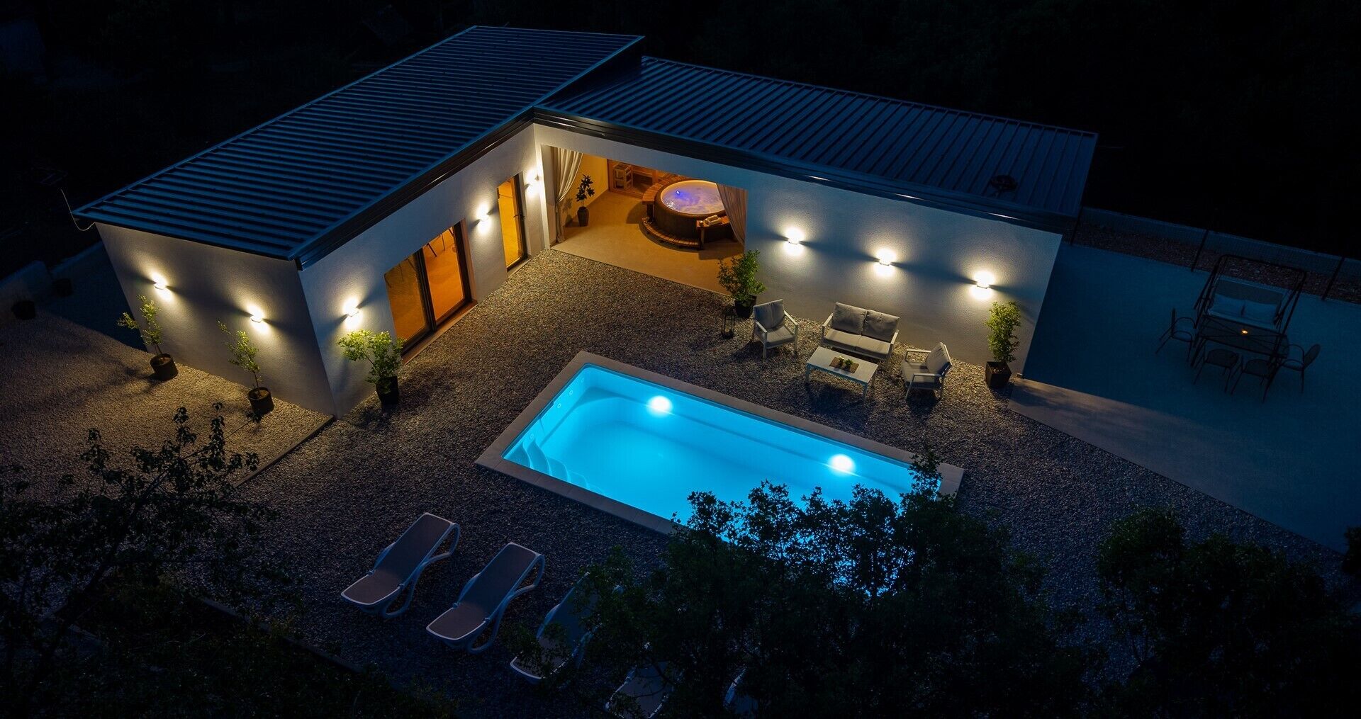 A modern house with a swimming pool, outdoor seating, and a hot tub.