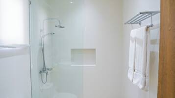 Chuveiro, toalhas de banho, shampoo, papel higiênico